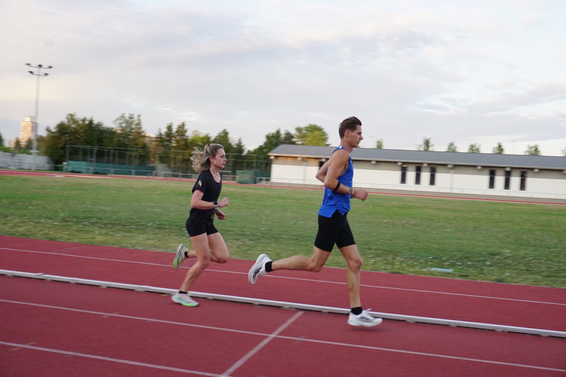 Julienn and Berci running an interval session together on a red athletics track